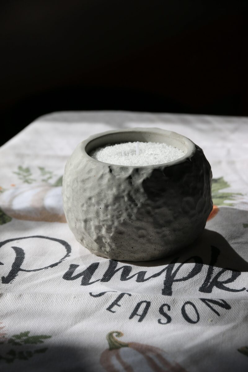 Kráteres beton tál fehér homokviasszal töltve, pamut kanóccal, Pumpkin Season feliratú terítőn.