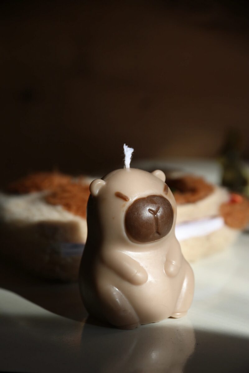 Ülő capybara gyertya mokka színben, pamut kanóccal, meleg fényben.