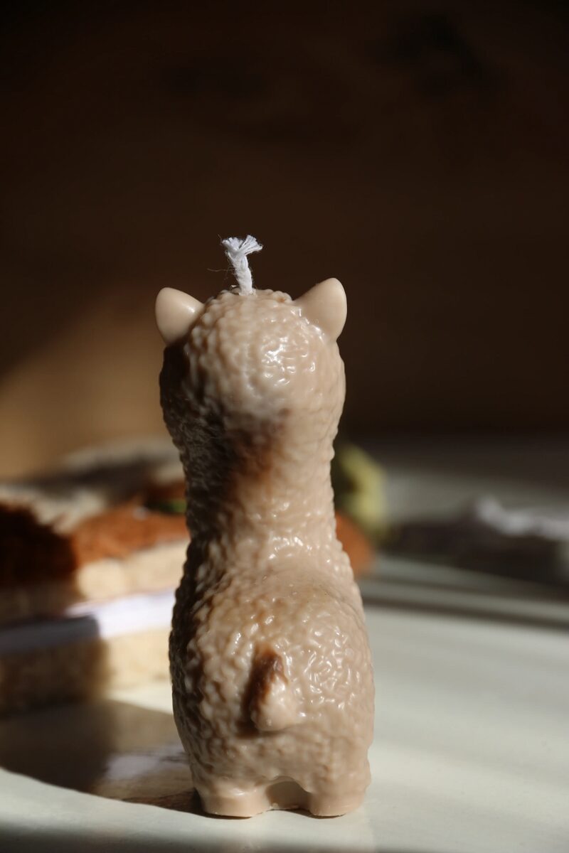 Mokka színű láma alakú gyertya hátulnézetből, a farok és a bunda mintázatával.