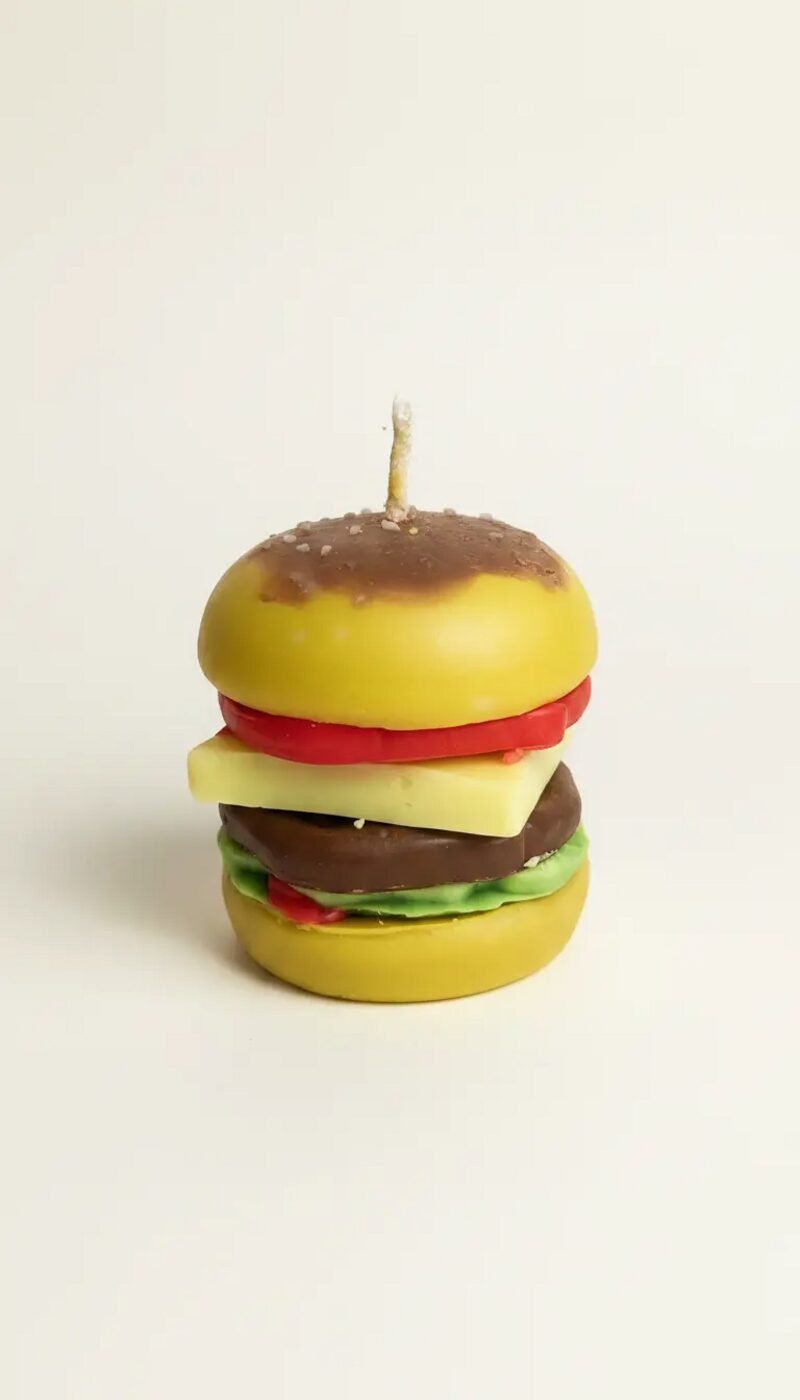 Hamburger alakú, sárga buci, piros paradicsom, sárga sajt, barna húspogácsa és zöld saláta rétegekkel, barna fedővel, gyertyával.