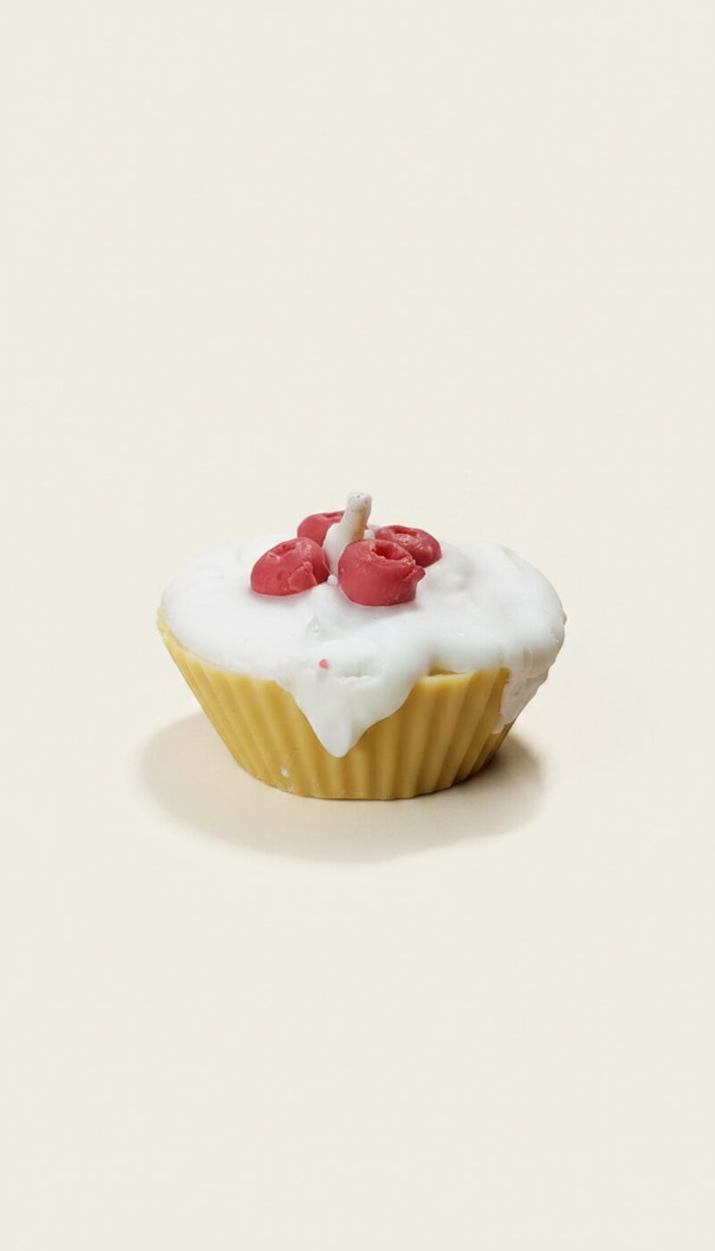 Áfonyás muffin formájú, sárga viaszgyertya fehér mázzal és piros bogyókkal.