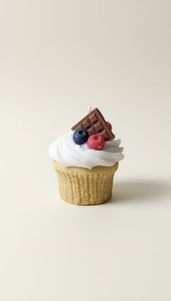 Áfonyás muffin formájú szójaviasz gyertya fehér krémmel, áfonyával, málnával és csokoládéval.
