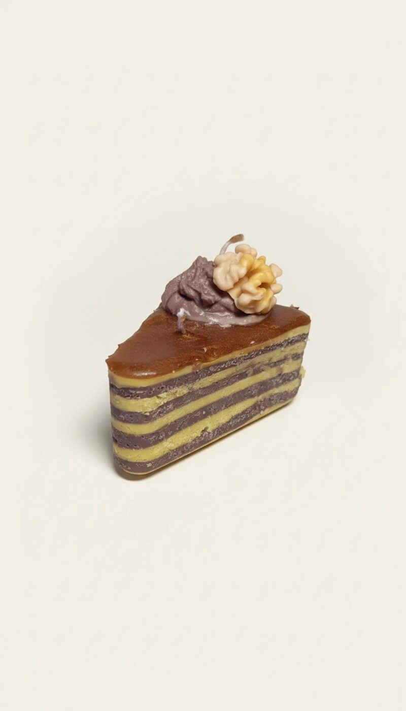 Diós színű tortaszelet gyertya, réteges kialakítással, csokoládé mázzal és díszítéssel.