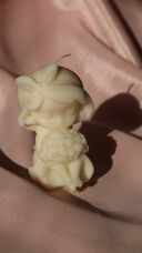 Natúr krémszínű szójaviasz gyertya: kalapos kislány figura, ölében nagy virágcsokorral.