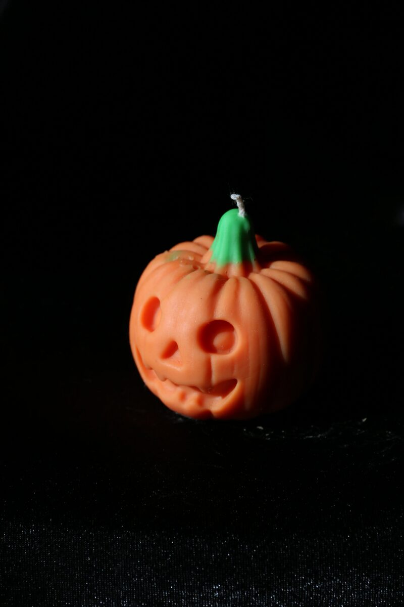 Kerek szemű Halloween tök gyertya oldalról, bordázott tökhéjjal.