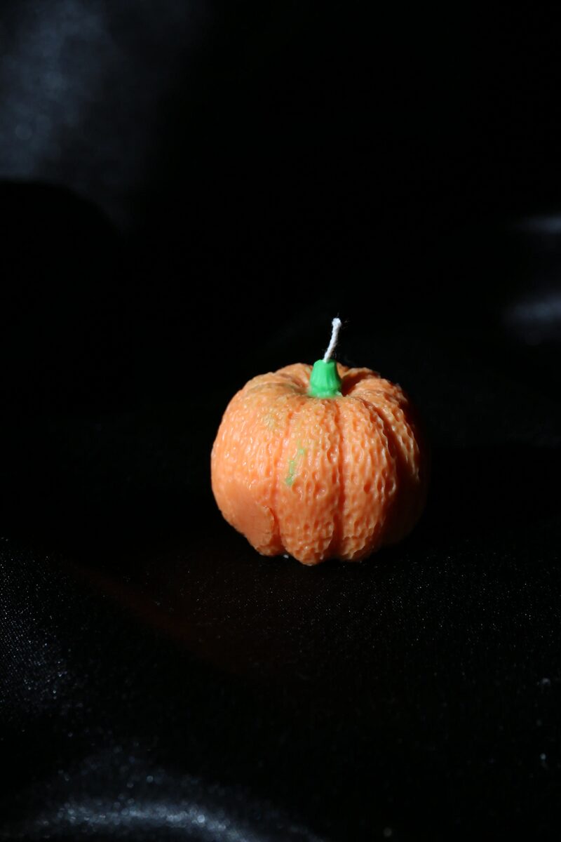 Mini bordás tök gyertya oldalról, fekete szatén háttéren.