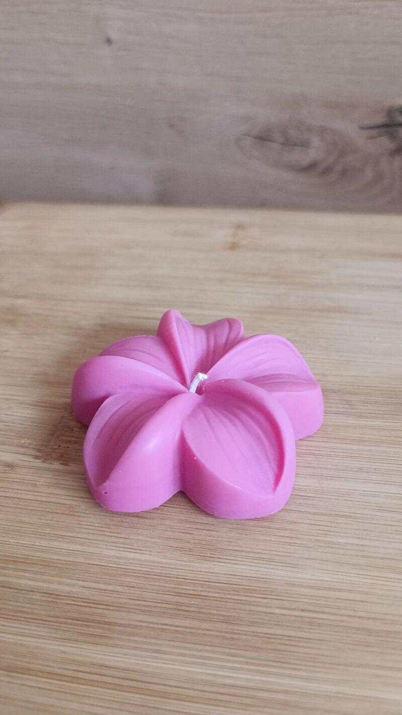 Kézműves plumeria formagyertya oldalról, lapos, alacsony virágformával.