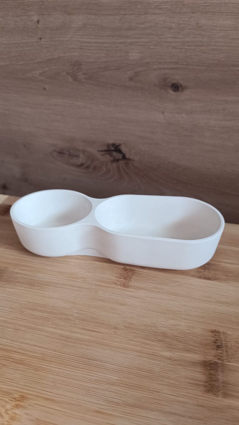 Üres, matt fehér dupla öböl kerámia tálca oldalnézetből, a kerek és az ovális öböllel.