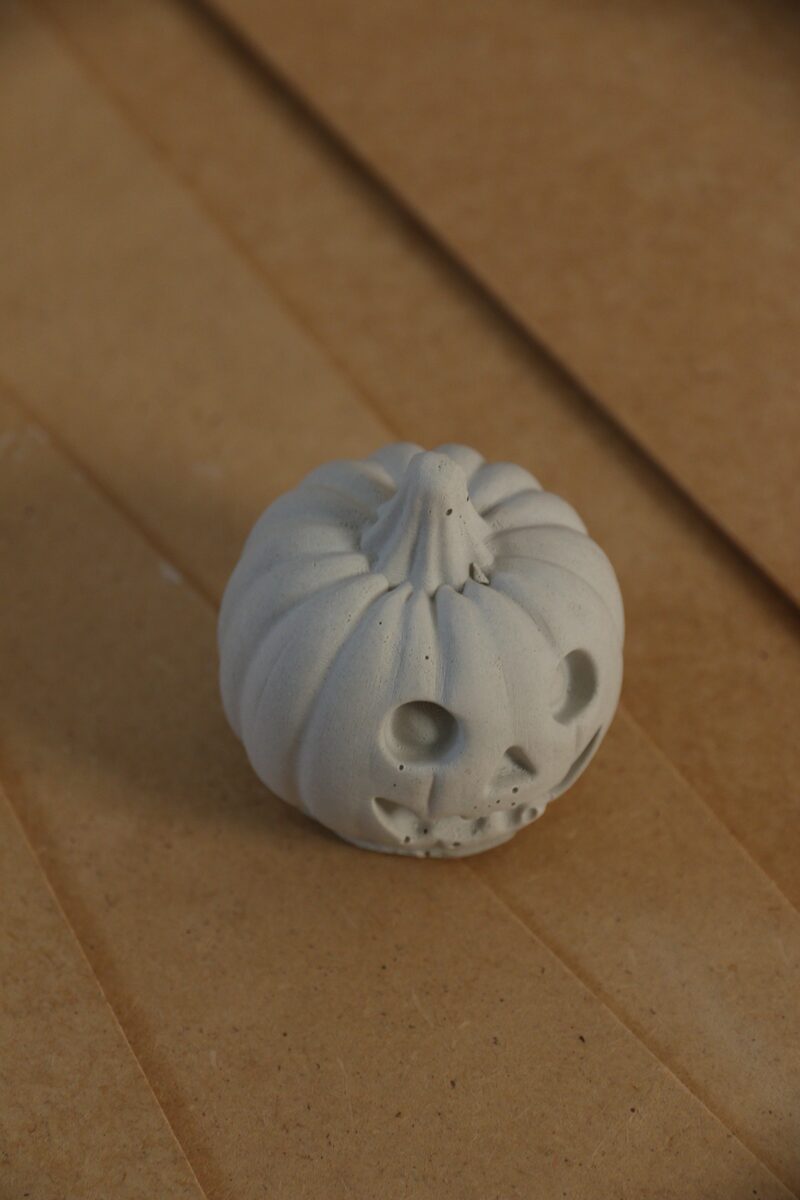Kerek szemű gipsz töklámpás oldalról, kreatív Halloween figura.